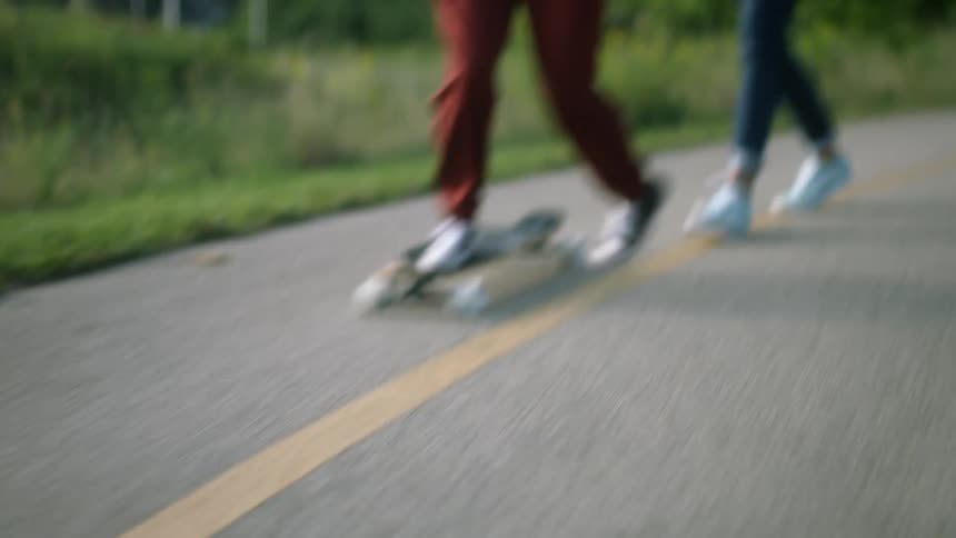 Point of view shot of two friends riding skateboards on a country road