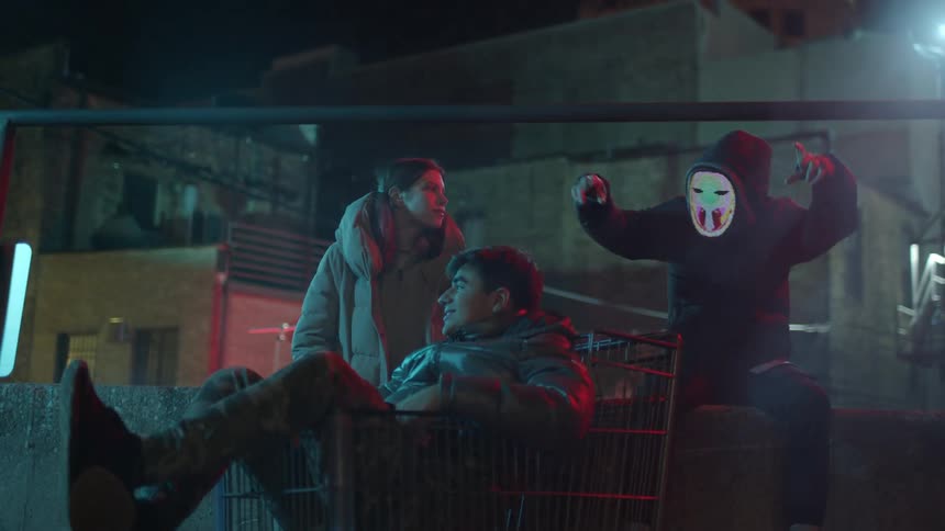 Two teen boys and a teen girl hanging out in the hood on a cold fall night having fun