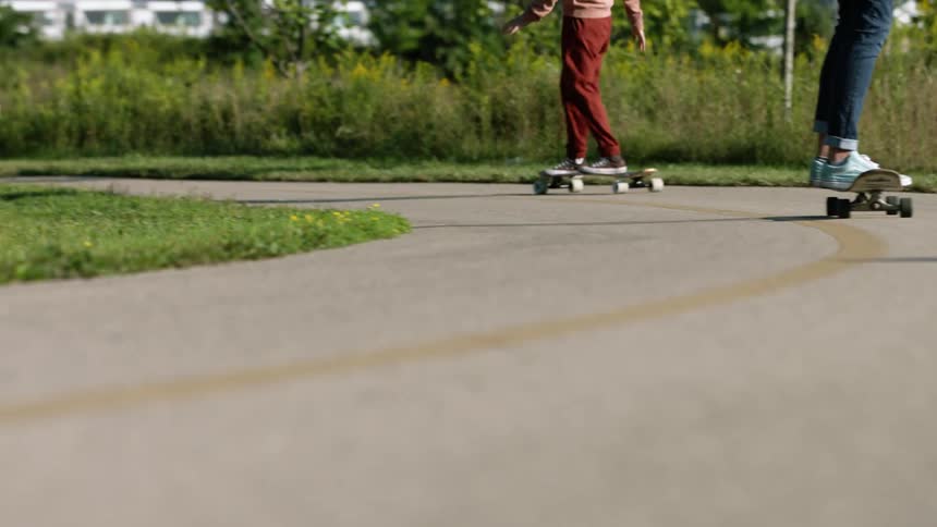 Two teens boy and girl riding skateboards on a country road