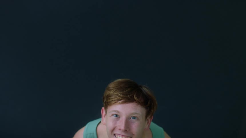 A boy smiling and jumping up and down in a green tank top