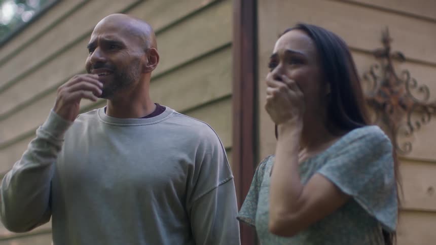 Couple walk to edge of house and stare at what they see surprise then side hug happily