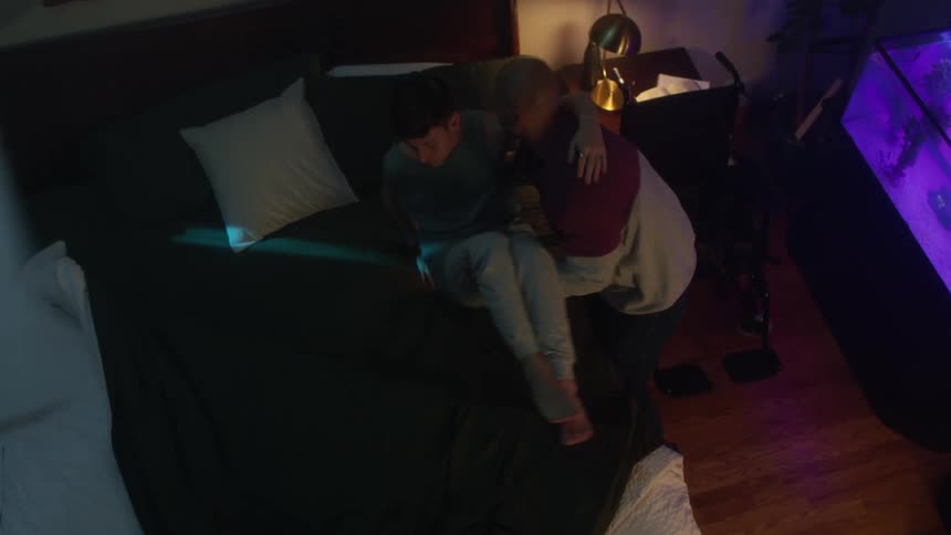 Man lifts youth from wheelchair near aquarium and places him on bed