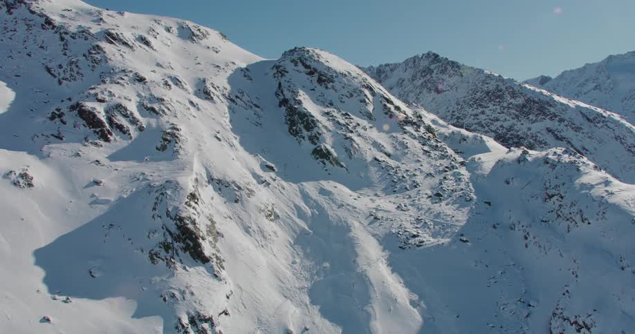 An aerial view of a snow covered mountain with tall peaks