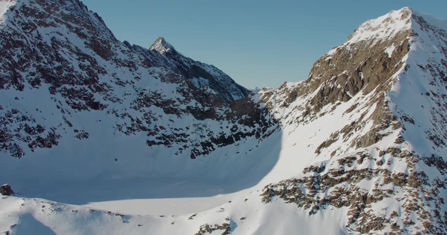 Snow covered mountain range stands partly in sun and partly in shadow