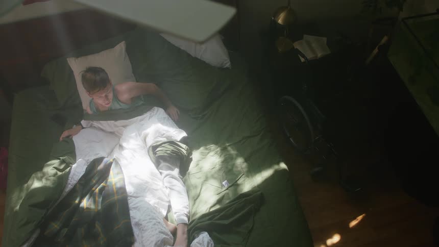 A man in his bed waking up and getting out of bed
