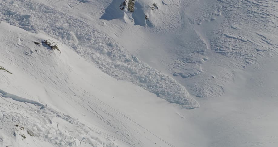 Avalanche falls down the side of a snowy mountain