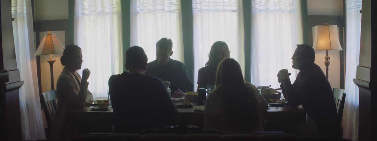 Two men stand after eating leaving the other people at the dining table