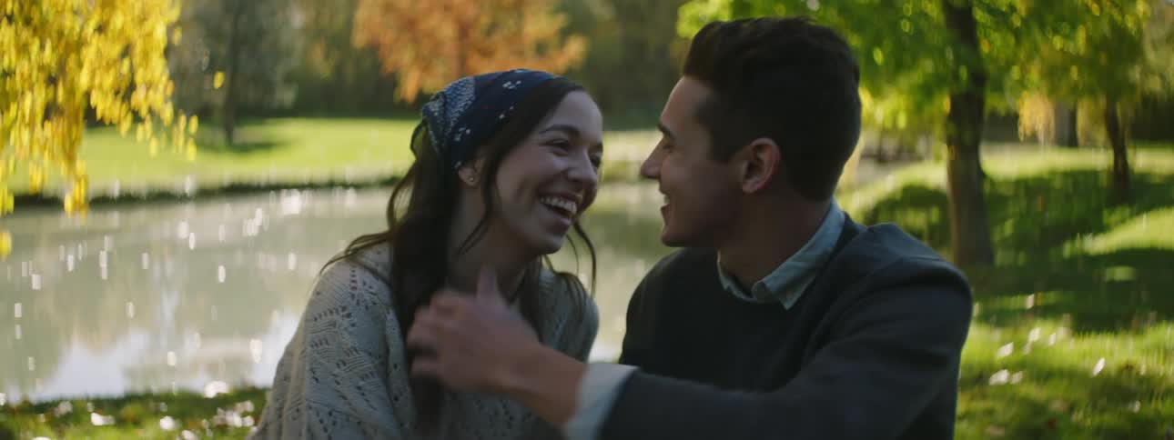 A man and woman sitting together smiling laughing with water in the background