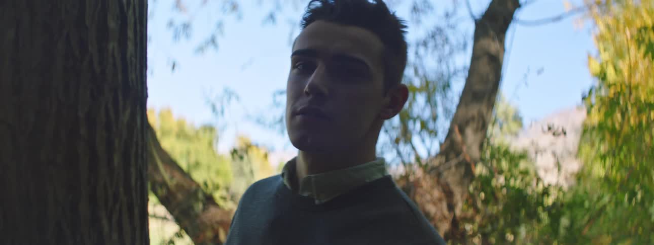 Man standing near tree turns and smiles