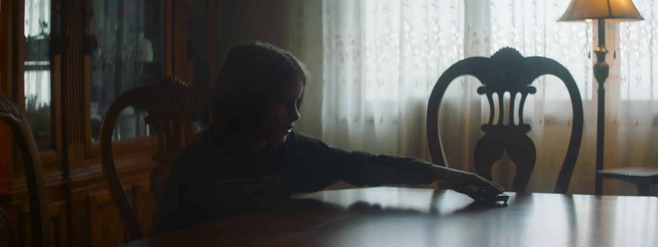 Child with sweatshirt sits at dining table playing with toy car
