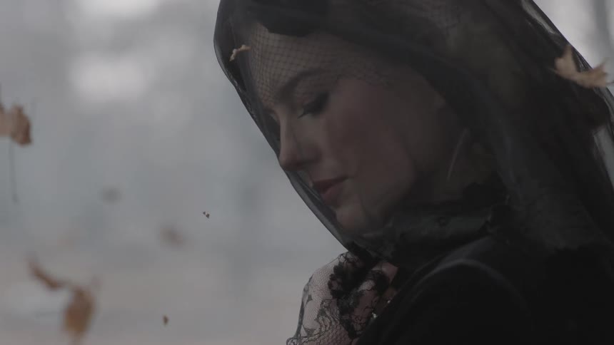 Veiled woman mourning on a windy fall day
