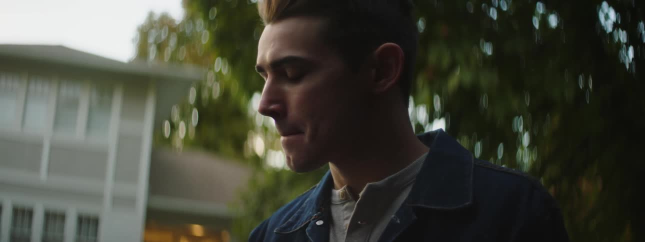Man with denim jacket gives car keys to man in the countryside smiling