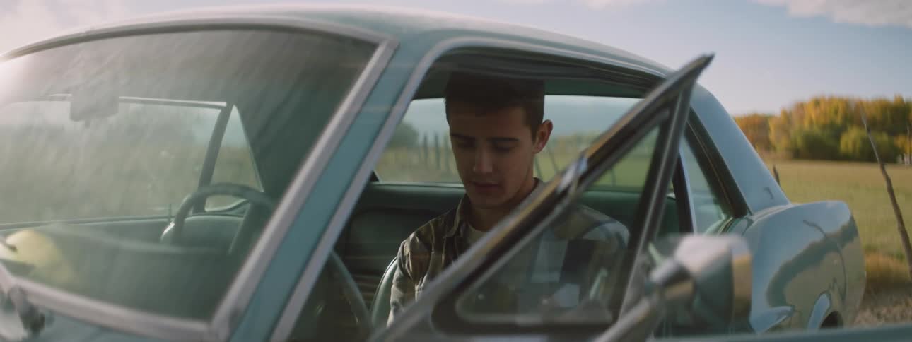 Sad man sitting in classic car reads a letter in the field