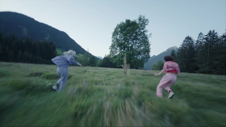 A mother and her daughter having fun by running towards a tree