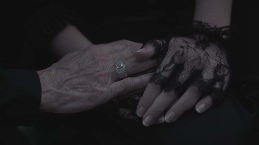 An older woman touches a younger woman's hands