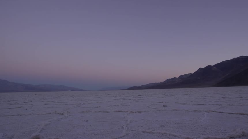 A large field and mountains are shown at sunset