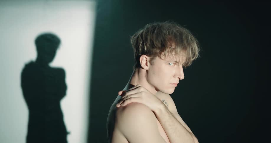 A man standing with his arms across his chest looking upset as a light flashes across him