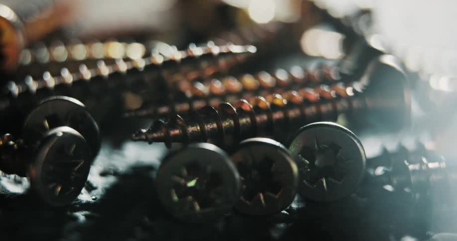 A handful of screws sits on a table as a time lapse shows the sun shining on them and eventually darkness surrounding them
