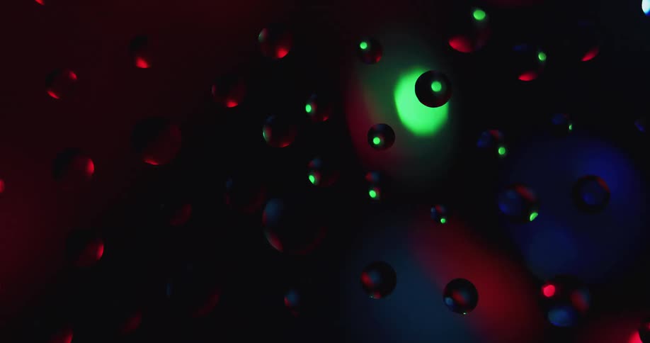 A close view of water beads refracting the multicolored lights on a spinning party ball in a dark room