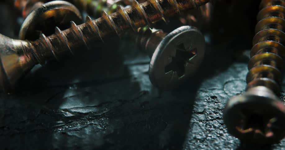 An up close of screws laid over each other as shadows are cast across them
