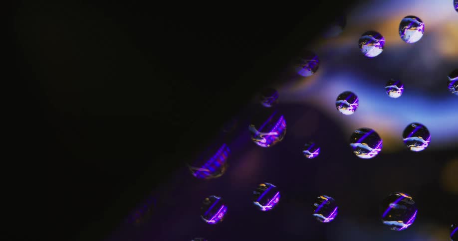 Water droplets on a window with reflections across it