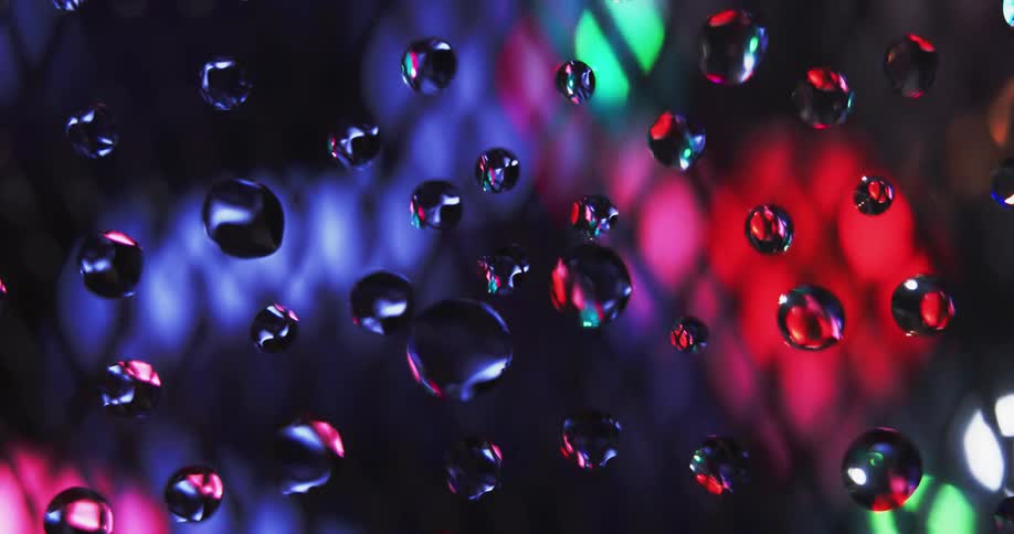 An up close of droplets with mesh and colors spinning in the background