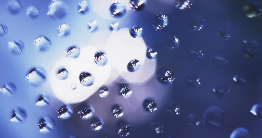 Colored lights shine on water droplets as the light reflects on the drops