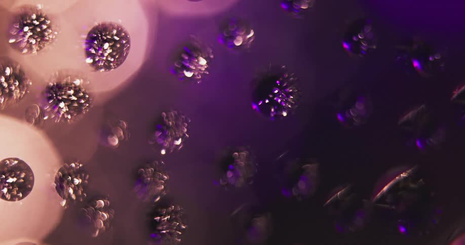 Closeup of water droplets on glass reflecting alternating red white and purple lights rotating behind it