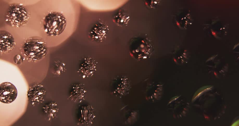Textured spheres float as colored light shines and reflects on their surface as they turn