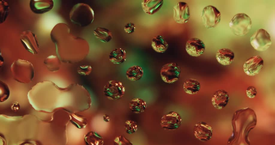 Water droplets are on clear glass as orange and yellow with a bit of green light shines behind them