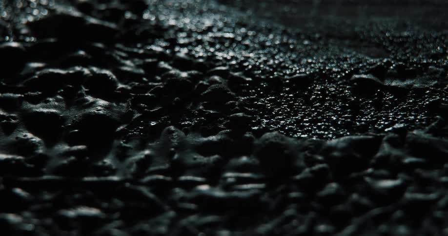 Tar bubbles on asphalt surface as dark falls