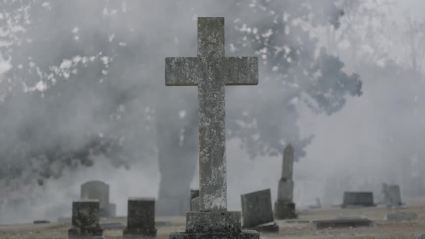 Mist rolls among gravestones in a cemetery