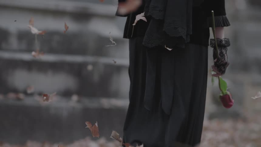 Leaves fall on a woman carrying a rose