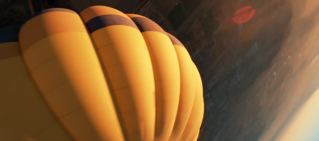 A hot air balloon flies above the countryside during the day