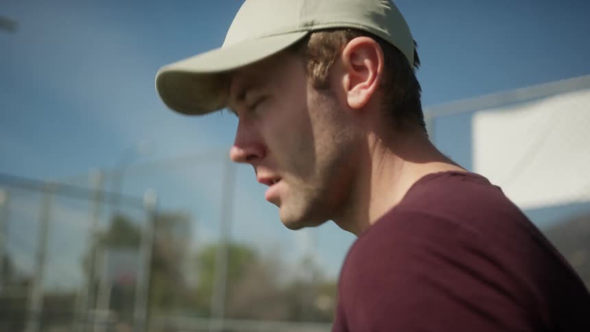 Tennis player prepares to serve backed by tall fence