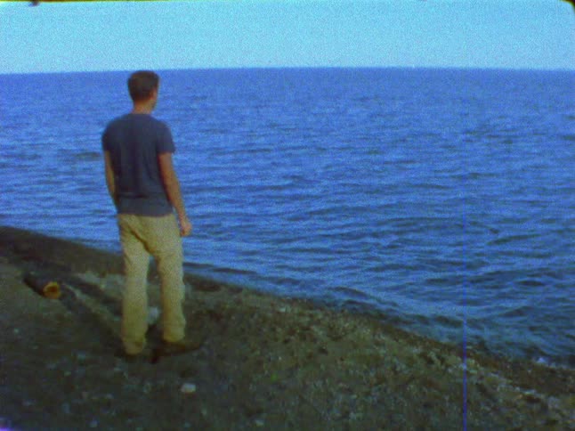 A man tries unsuccessfully to skip stones across the ocean during the day