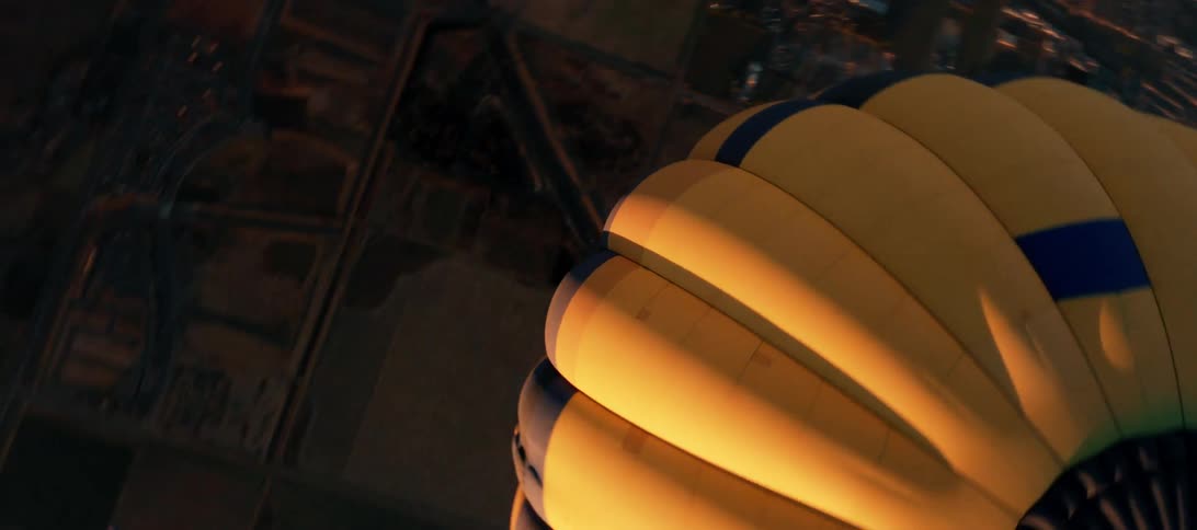 A hot air balloon flies over a dense suburb