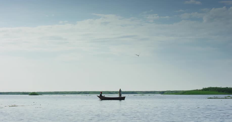 Fishermen on boat cast a net on water