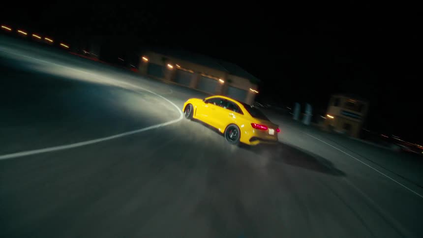 A yellow automobile slides as it speeds around a curve