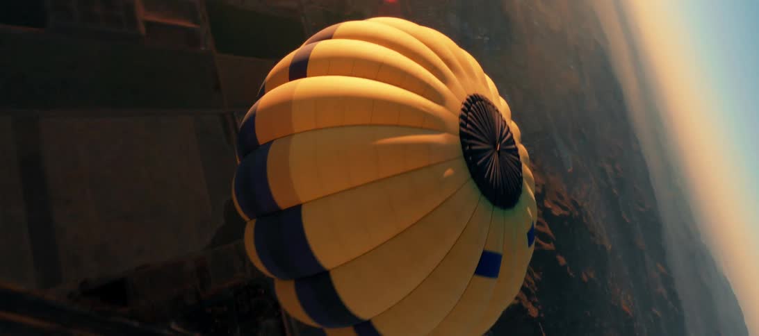 A hot air balloon travels above a countryside during the day