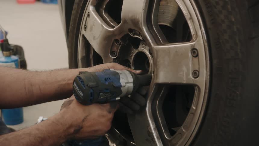 A mechanic removes lug nuts from a vehicles tire