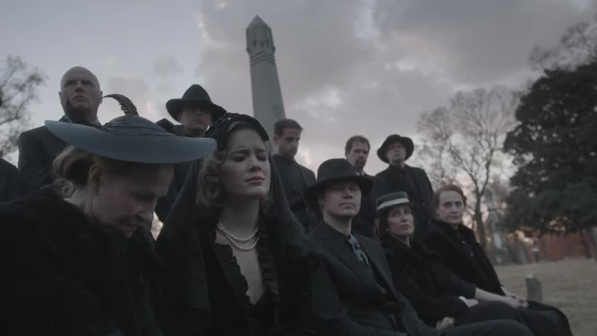 People mourning at a funeral outside in a cemetery