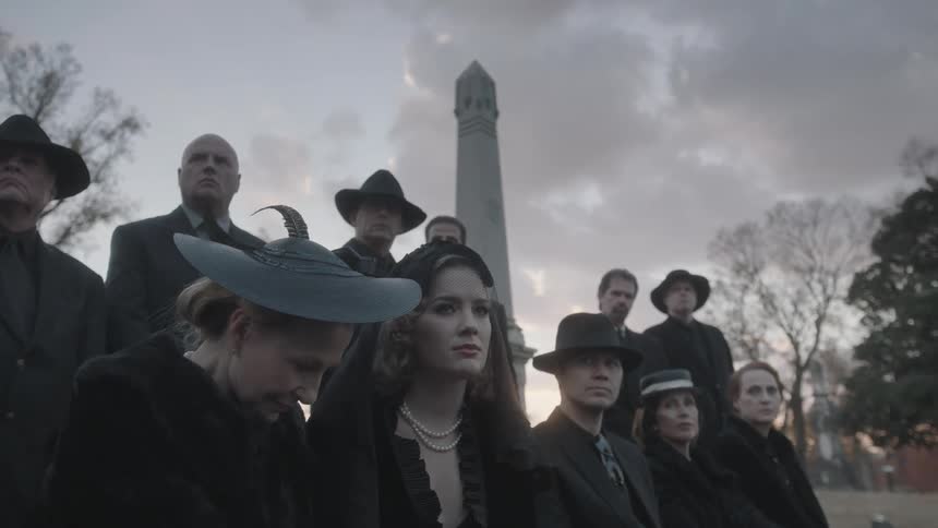 A group of people mourn at a graveside funeral service