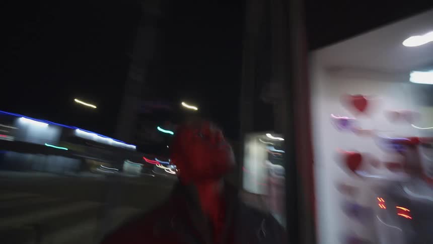 Man walks along street passing clothes store at night