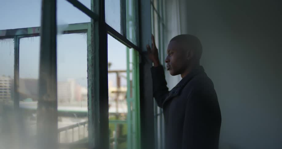 A man staring out the window contemplatively on a bright day