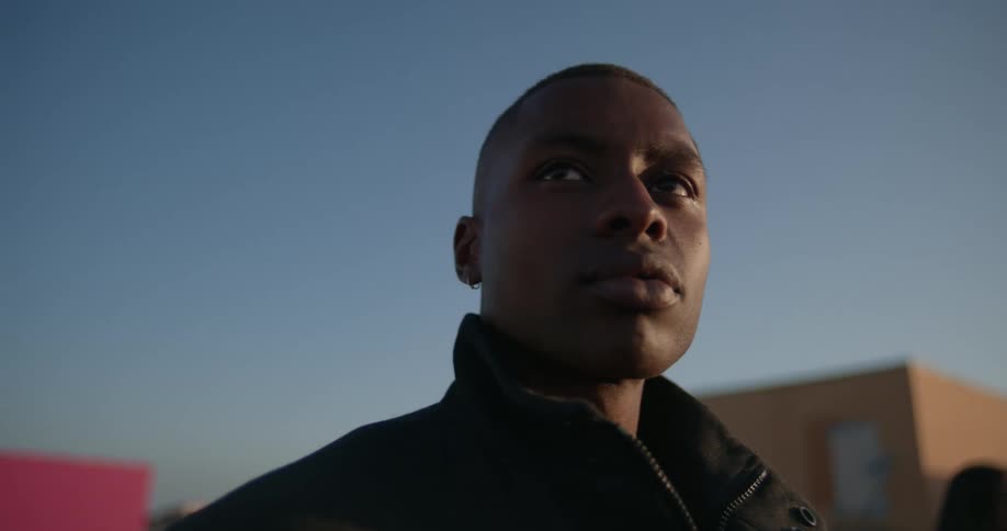 Man stands outdoors near buildings under a clear blue sky
