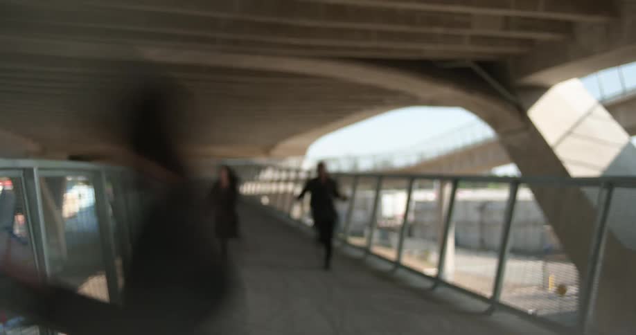 Three people running across a bridge walkway