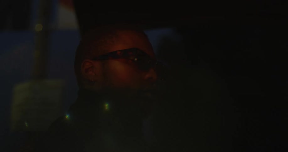 An up close of a mans face with glasses on and a red light flashing on his face