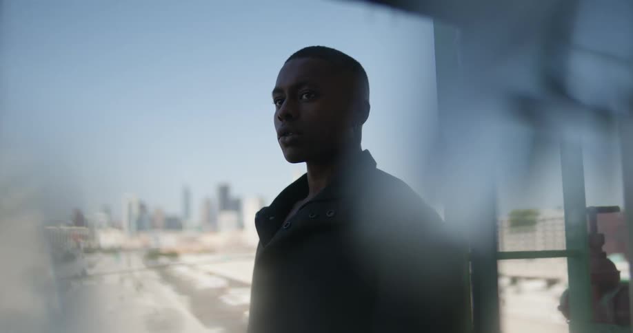 Dingy windows slightly blur image of city skyline as man stand just outside window