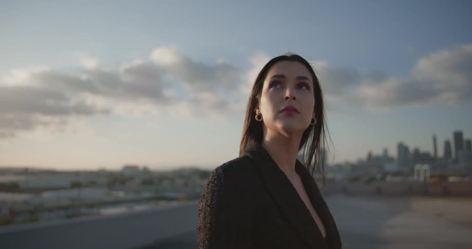 Woman looks around while on building room with skyline in the distance